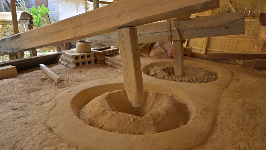Inside the hut, wooden pestles and mortars crush lumps of earth collected from the hills into fine clay.